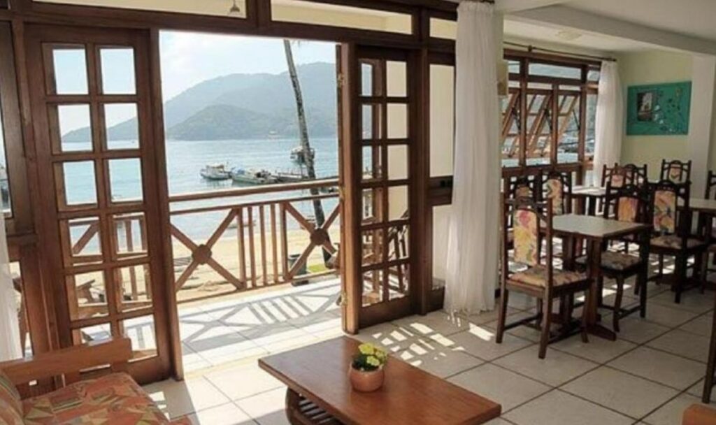 Bright dining room with wooden French doors opening onto waterfront balcony
