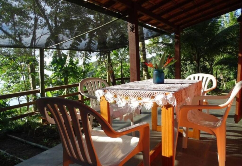 Covered terrace with dining table and tropical flowers overlooking lush rainforest vegetation