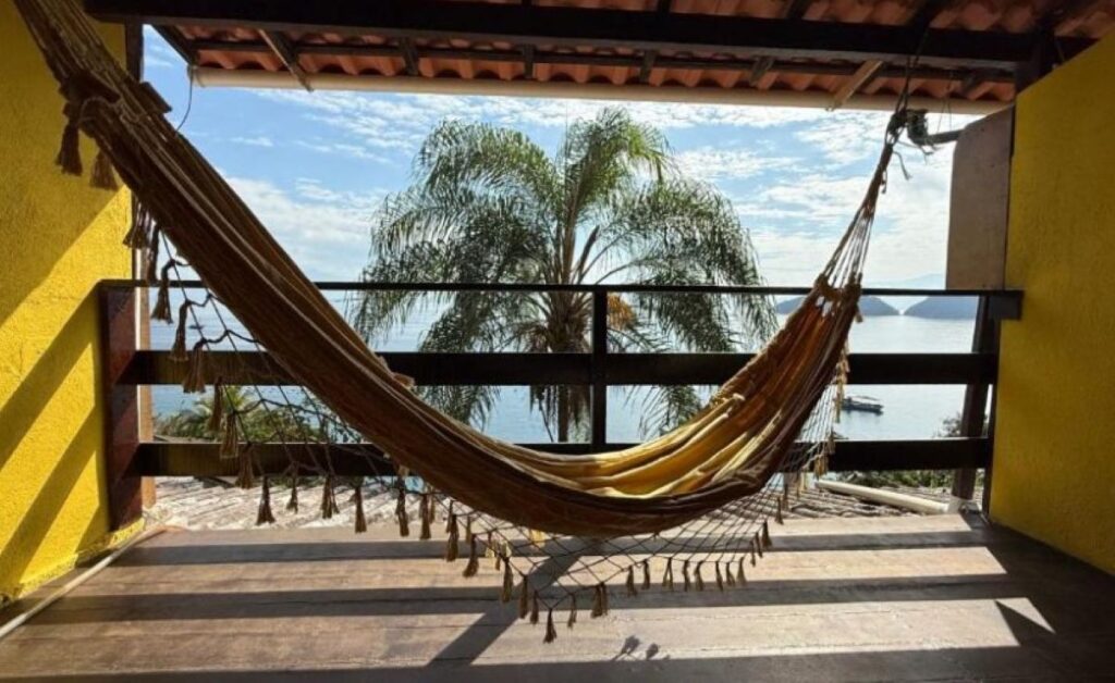 Hammock on covered balcony with ocean views and palm trees at Brazilian pousada