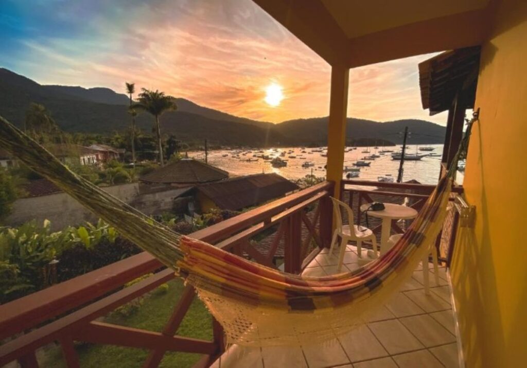 Balcony hammock at sunset overlooking harbour with anchored boats and forested mountains