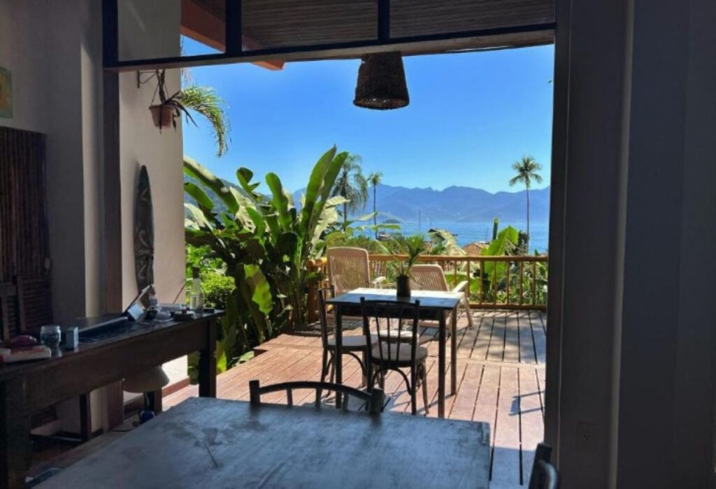 Open-plan kitchen and terrace with ocean and mountain views framed by tropical plants