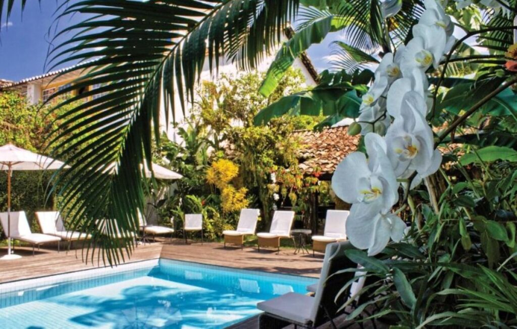 Tropical hotel pool surrounded by white orchids, palm fronds and sun loungers