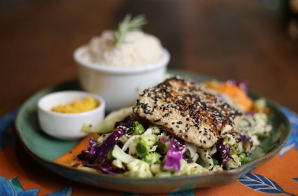 Sesame-crusted fish fillet on colourful slaw with rice and mustard sauce