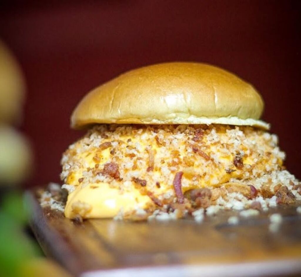 Burger with crispy coating, melted cheese and bacon crumbles on glazed bun