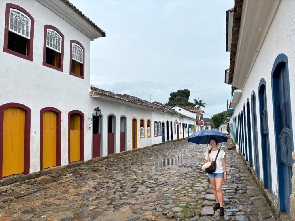 Tourist walking cobblestone street lined with colourful colonial buildings