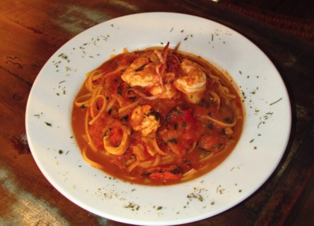 Seafood pasta with prawns in rich tomato sauce garnished with fresh herbs