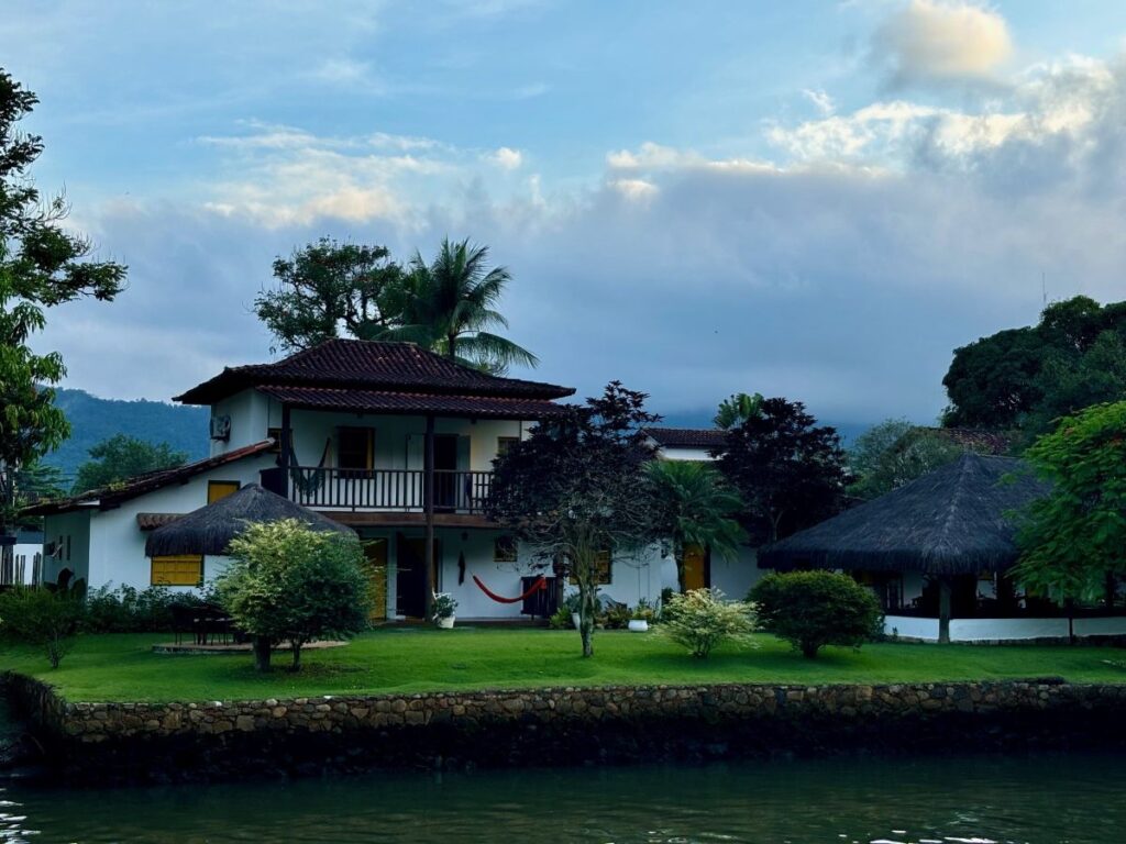 Traditional white colonial house with balcony beside waterway at dusk