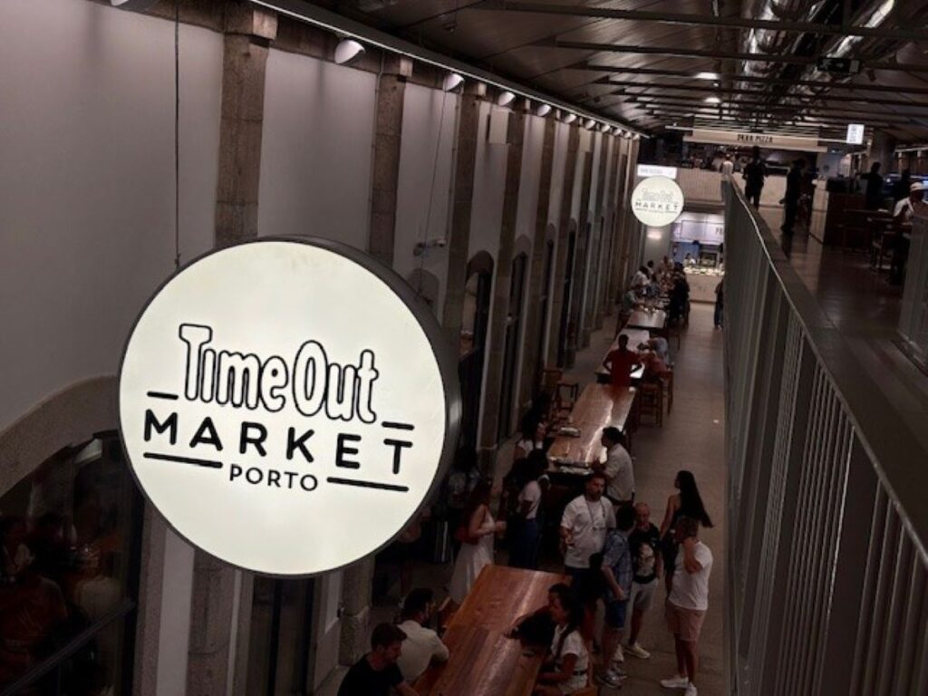 Time Out Market Porto illuminated sign overlooking indoor food hall seating area