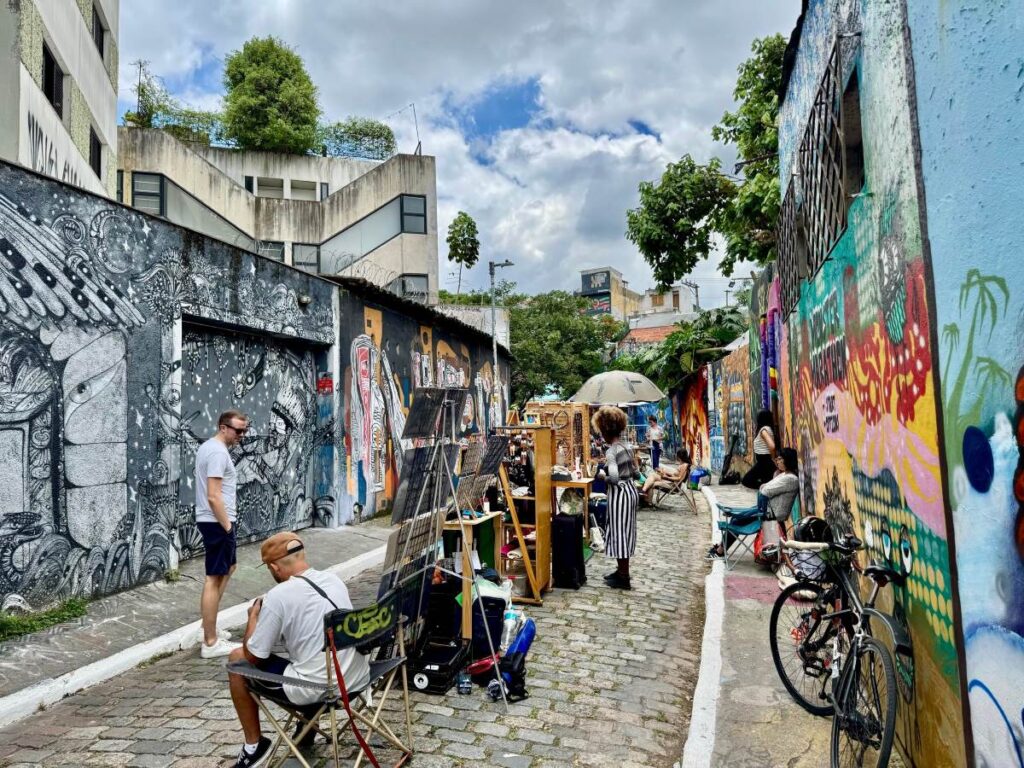 Beco do Batman alley in Vila Madalena, São Paulo, with graffiti walls, cobblestones, and artists at work