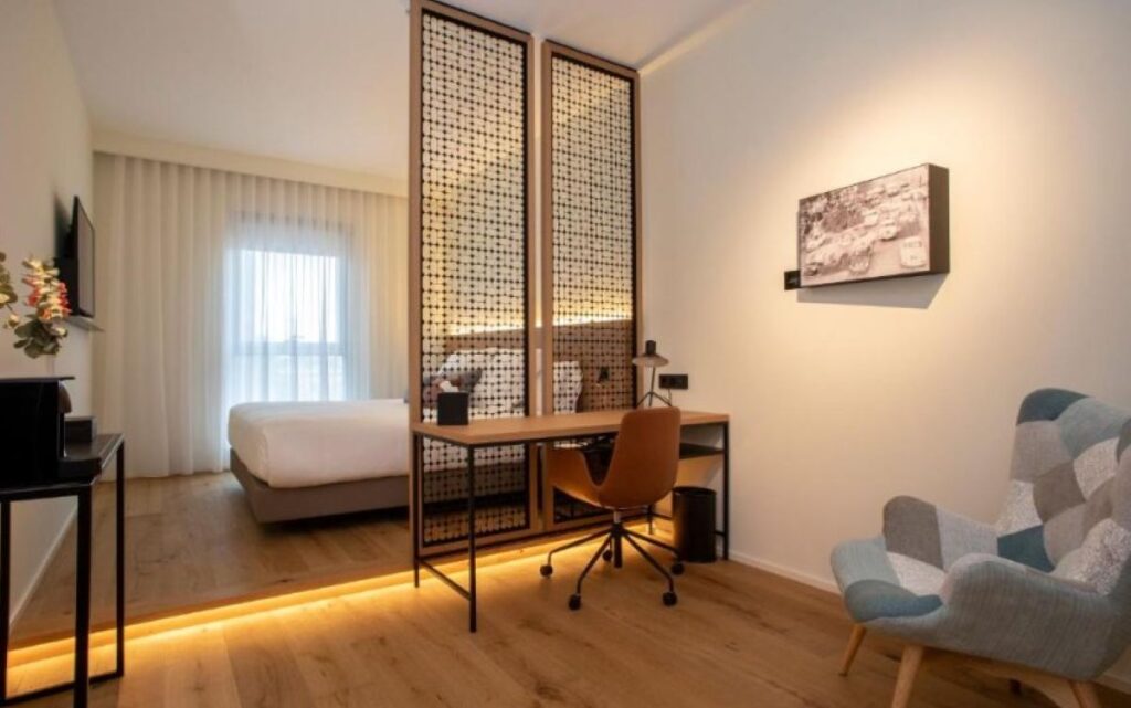 Contemporary room with tall ornate lattice room divider, wooden work desk, armchair and local city artwork