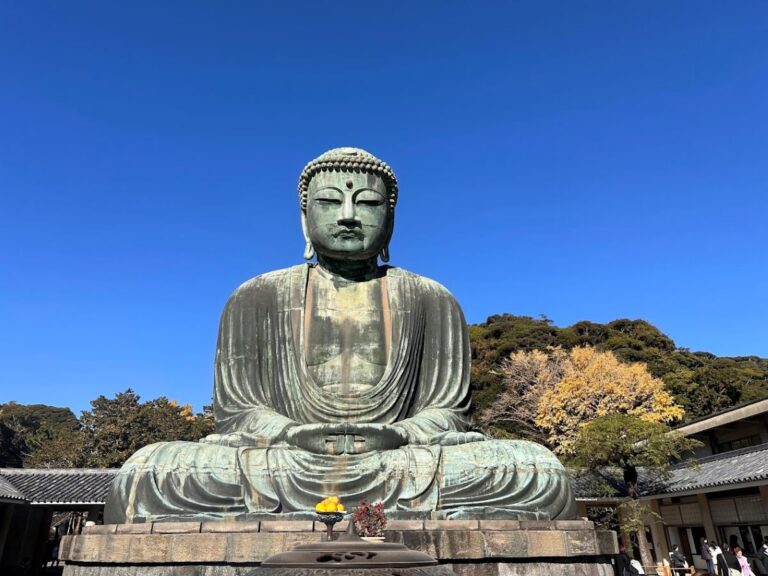 Kamakura Great Buddha at Kōtoku-in, bronze statue seated under a clear blue sky with trees behind.