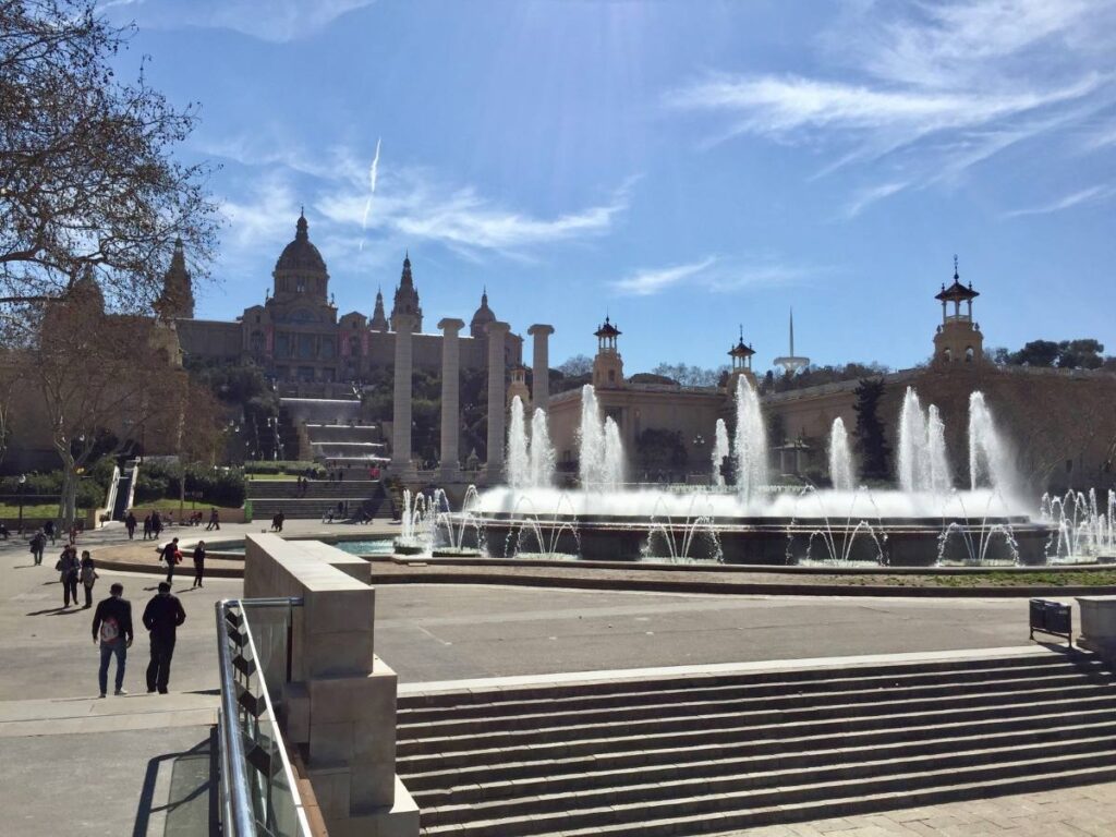 Plaça d’Espanya fountains spraying in front of the Venetian towers, with MNAC on Montjuïc in the background.