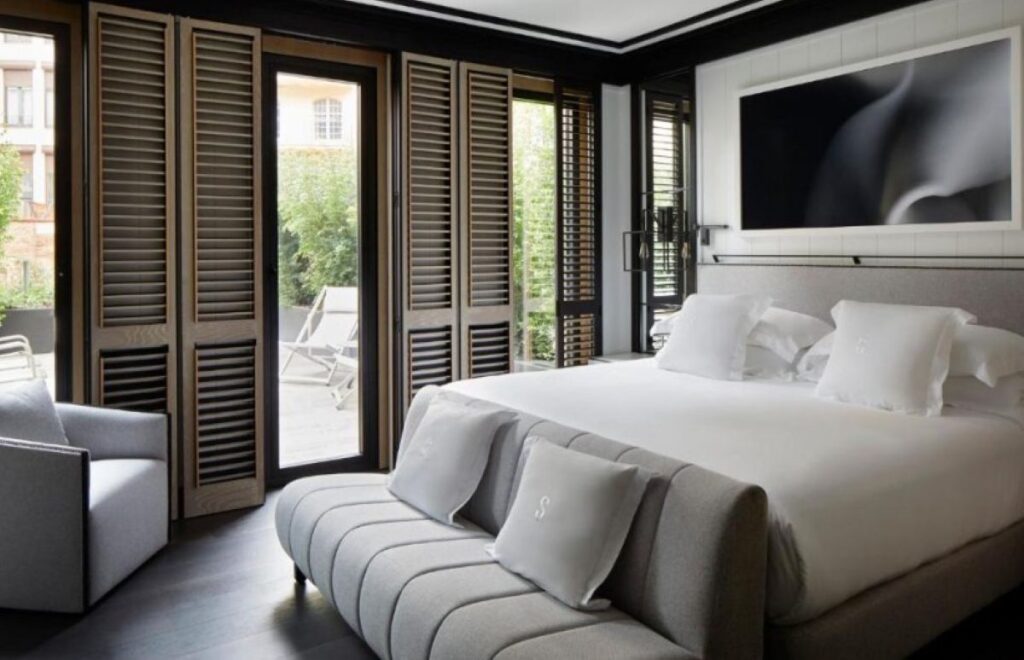 Sophisticated dark-toned suite with full-height louvred shutters, king bed and private terrace with sun loungers