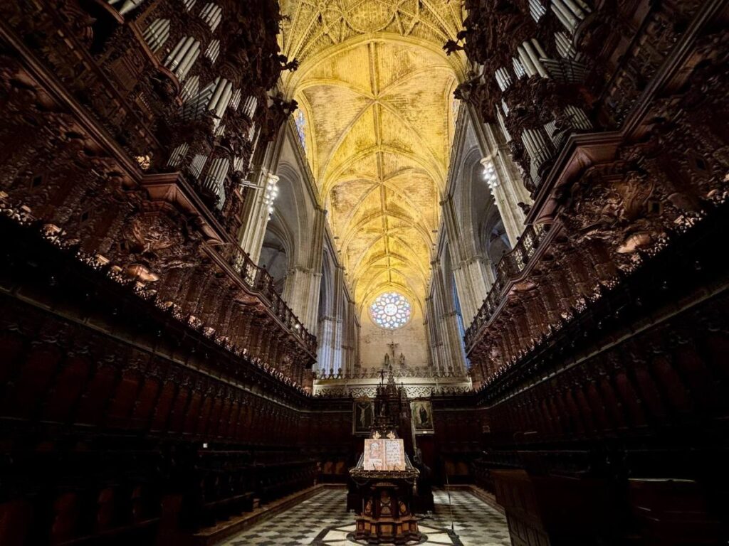 Cathedral choir stalls with dark carved wood, vaulted ceiling and a rose window.