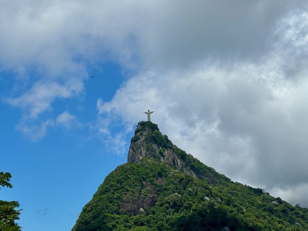 Christ the Redeemer statue on top of Corcovado mountain viewed from below, surrounded by the green canopy of Tijuca Forest