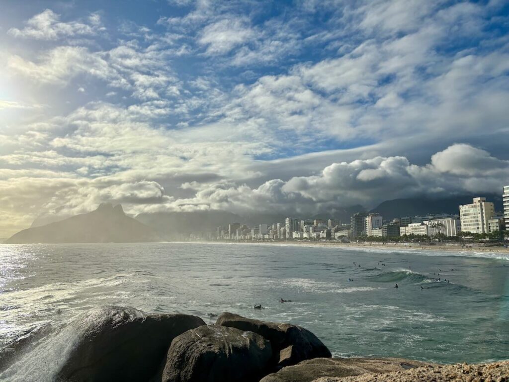 Ipanema Beach viewed from Arpoador, Two Brothers Mountain on the left, surfers in the foreground and dramatic clouds overhead