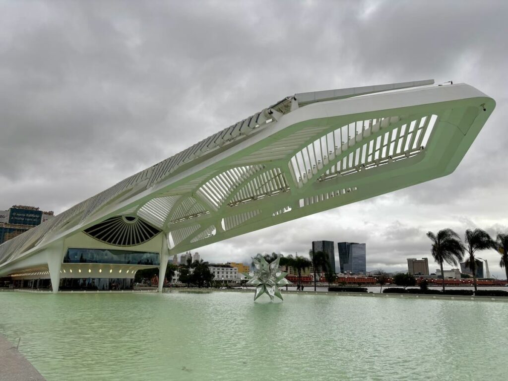 Museum of Tomorrow, futuristic white cantilevered building by Santiago Calatrava reflected in shallow pool on an overcast day