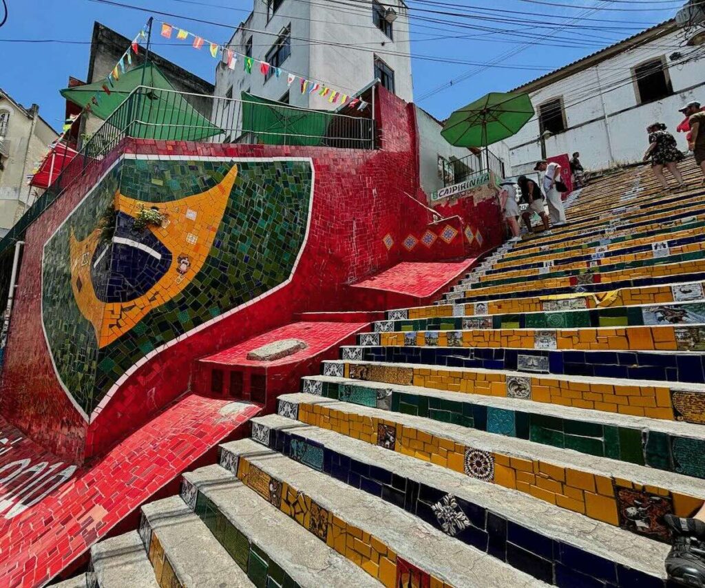 Escadaria Selarón, colourful tiled steps with a red Brazilian flag mosaic and yellow tiles leading up between Lapa houses