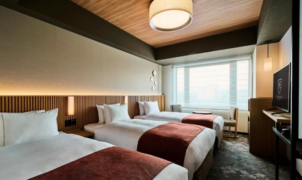 Royal Park Umekoji triple room with three single beds, wood-slatted headboards and a soft pendant ceiling light