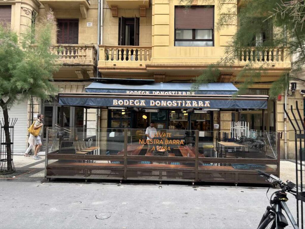 Exterior of Bodega Donostiarra in Gros, blue awning above a glazed outdoor seating area