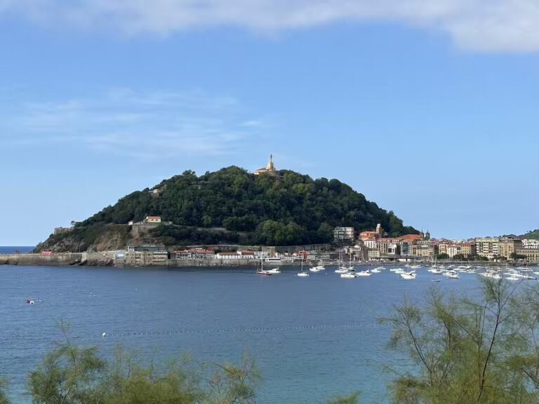 View across La Concha bay to Monte Urgull, with the statue of Christ on the summit and boats moored below