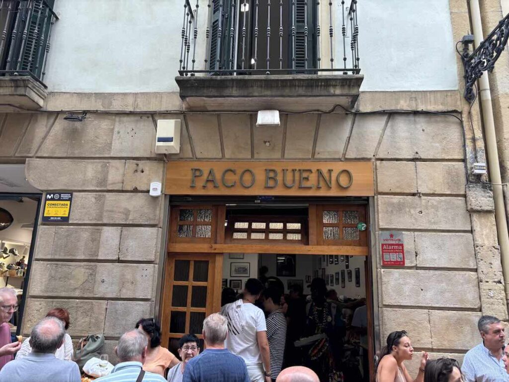 Customers eating and drinking on the street outside the entrance to Paco Bueno