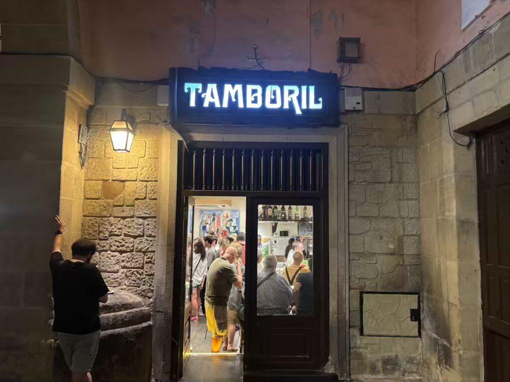 Tamboril's lit neon sign above a doorway at night, with a crowd standing at the counter inside