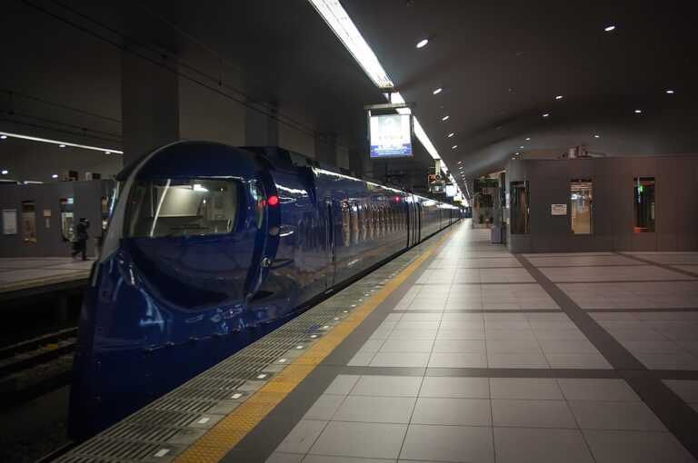 A Nankai Rapi:t train waiting at the platform at Kansai Airport Station, its blue nose and red tail lights lit under the station lighting.